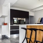 A contemporary kitchen featuring sleek cabinetry and elegant bar stools in a minimalist design.