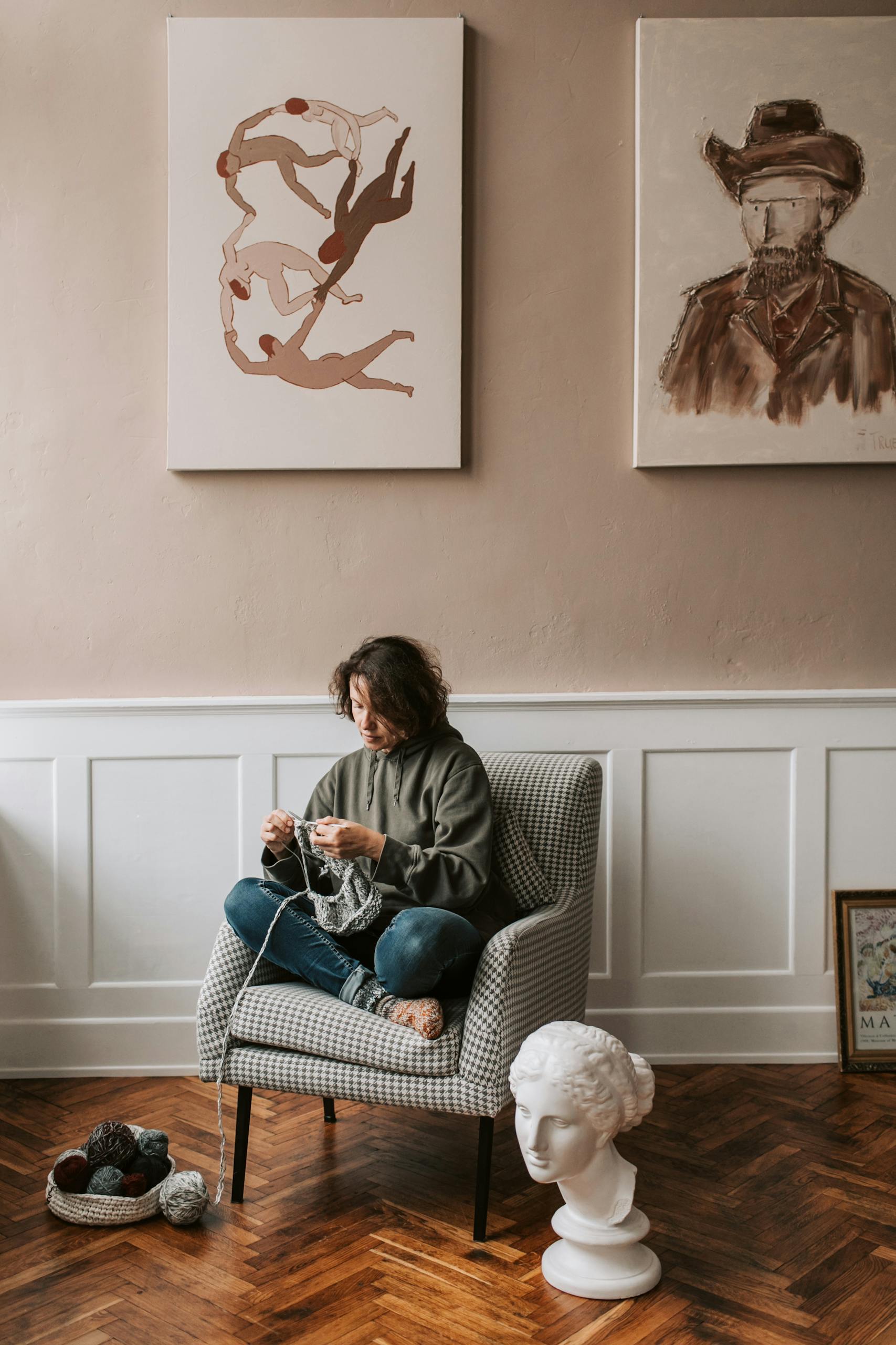 Calm indoor scene of a woman knitting in a stylish living room with artistic decor.