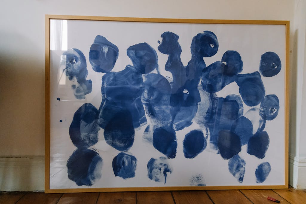 Modern abstract blue and white art exhibited in a simple wooden frame.