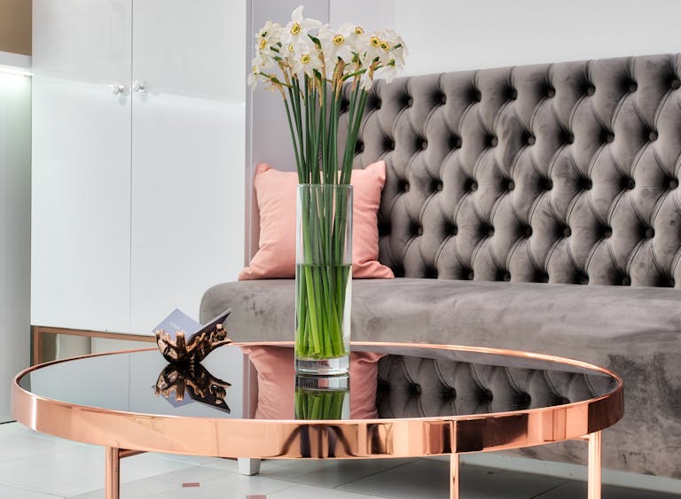 Modern interior showcasing a glass vase with narcissus flowers on a stylish metallic table.